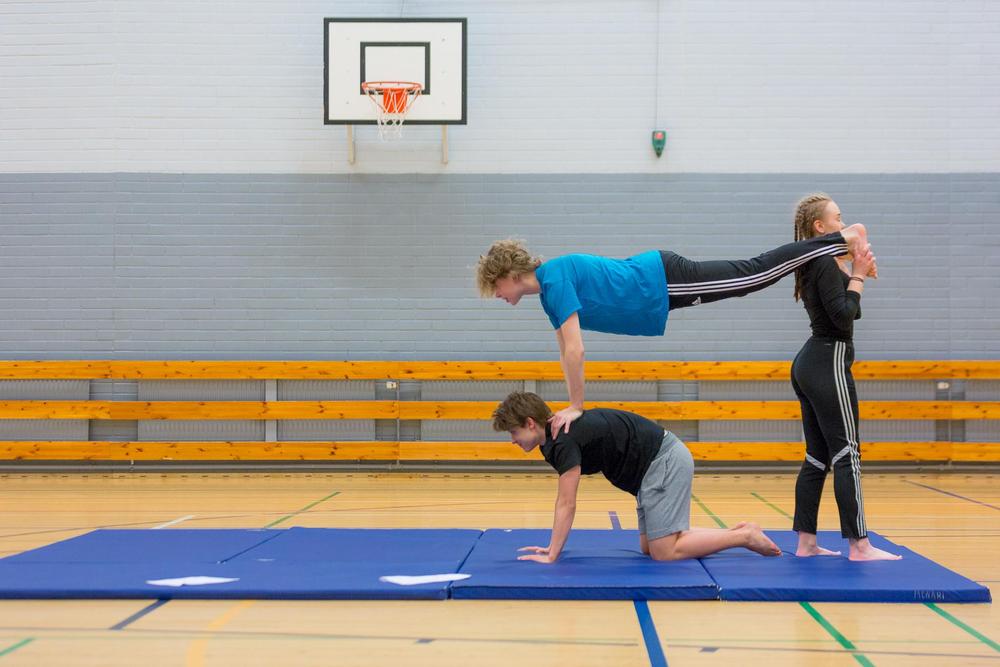 Kolme nuorta muodostamassa ihmispyramidia liikuntatunnin aikana.