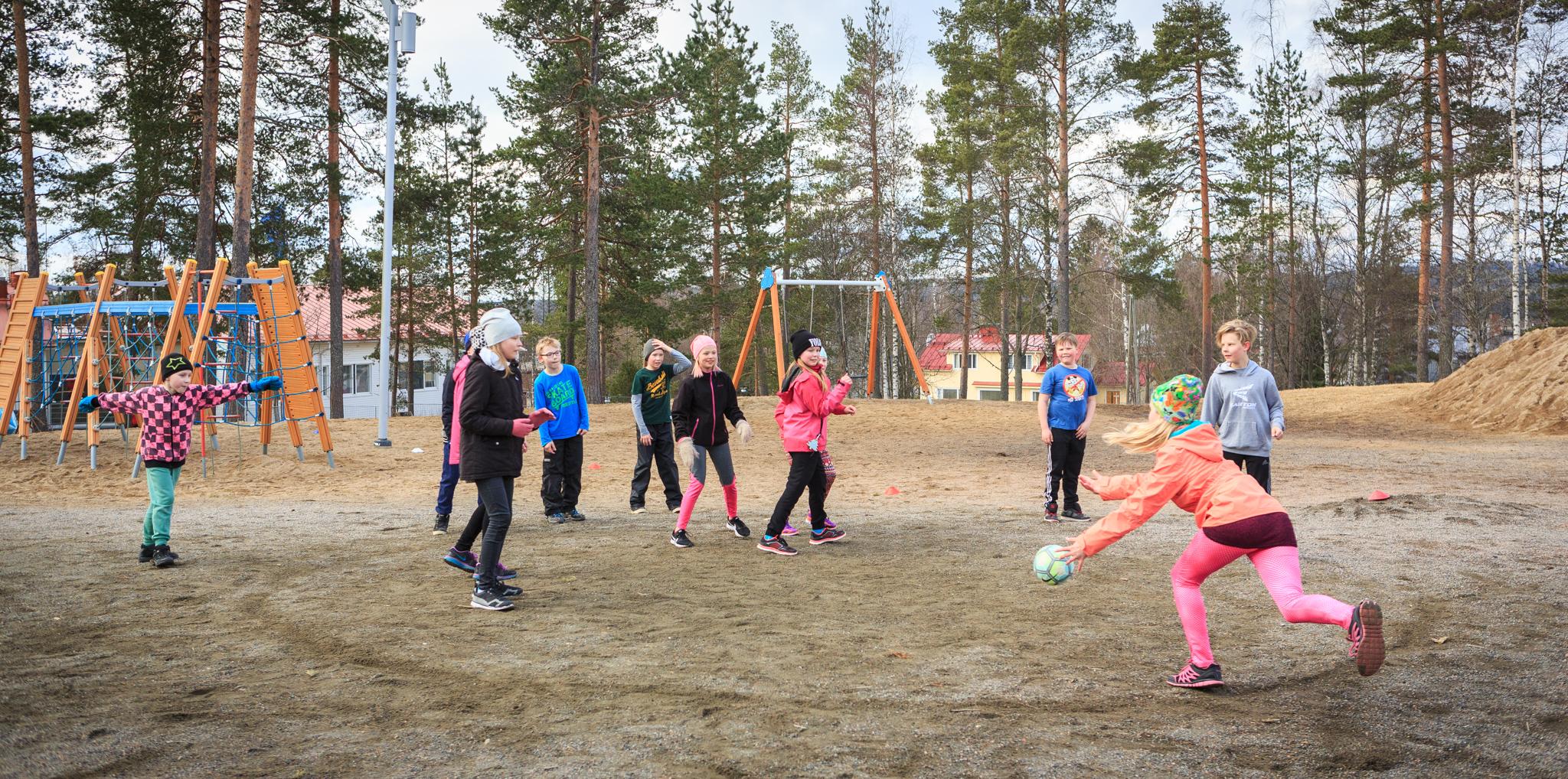 Kouluikäiset lapset pelaavat ulkona polttopalloa.