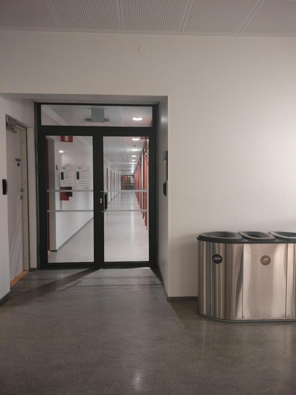 Kuva 1.rakennuksen (päärakennuksen) toisesta kerroksesta. Kuvassa näkyy lasiovet, jotka johdattavat käytävälle, jossa sijaitsee Pokalin työntekijöiden työhuoneet sekä kahvihuone.