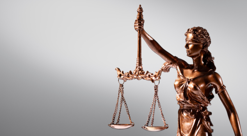 En bronsfärgad staty föreställande en kvinnlig figur som håller en våg i sin utsträckta hand. Figurens ögon är förbundna.