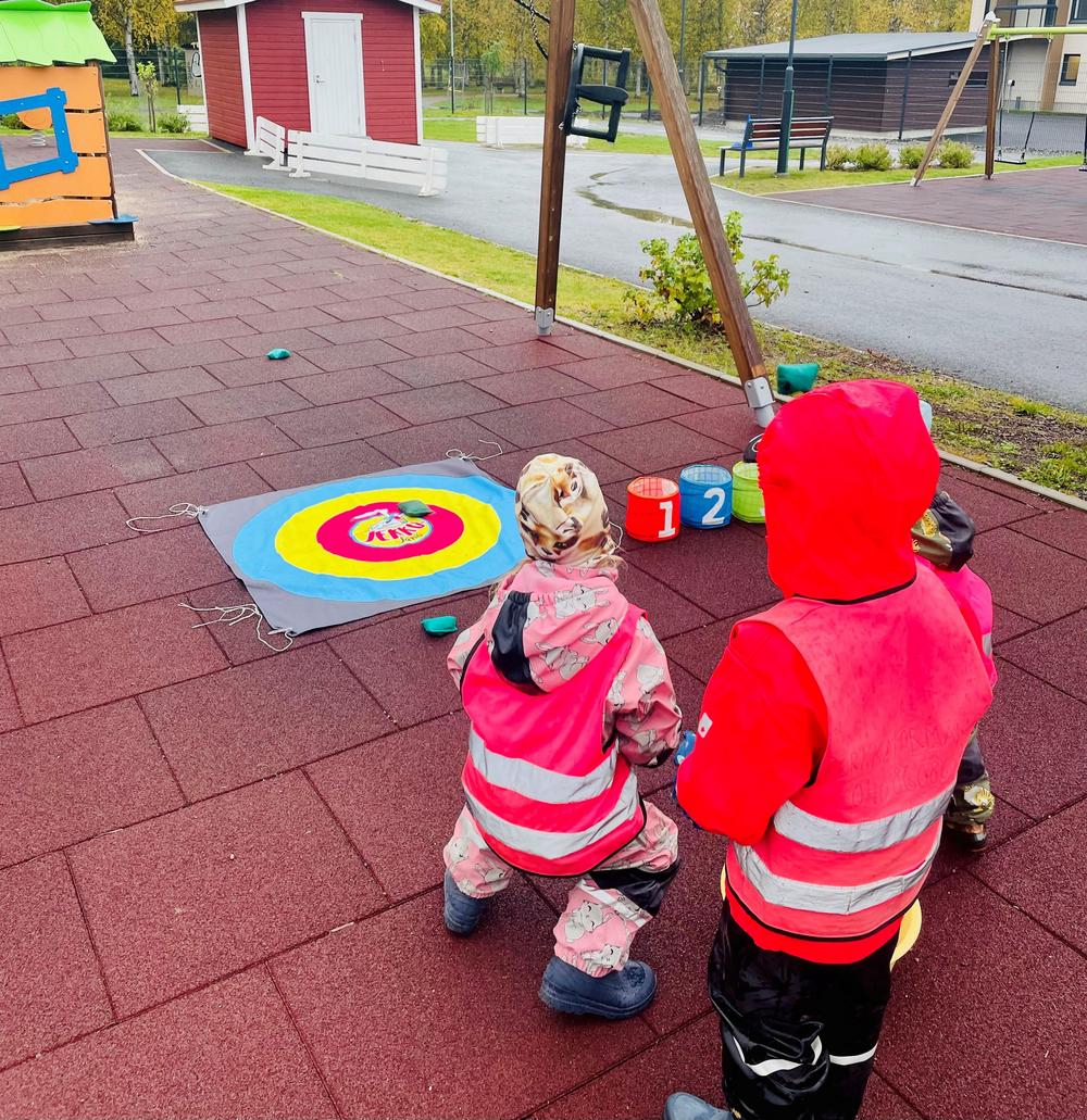 Kolme lasta harjoittelmassa Jekku-jänön heittoalustaan.