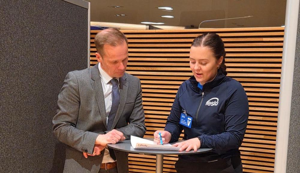 Markku Siponen ja Meri Moilanen seisovat korkean pöydän ääressä ja katsovat pöydällä olevaan paperiin.