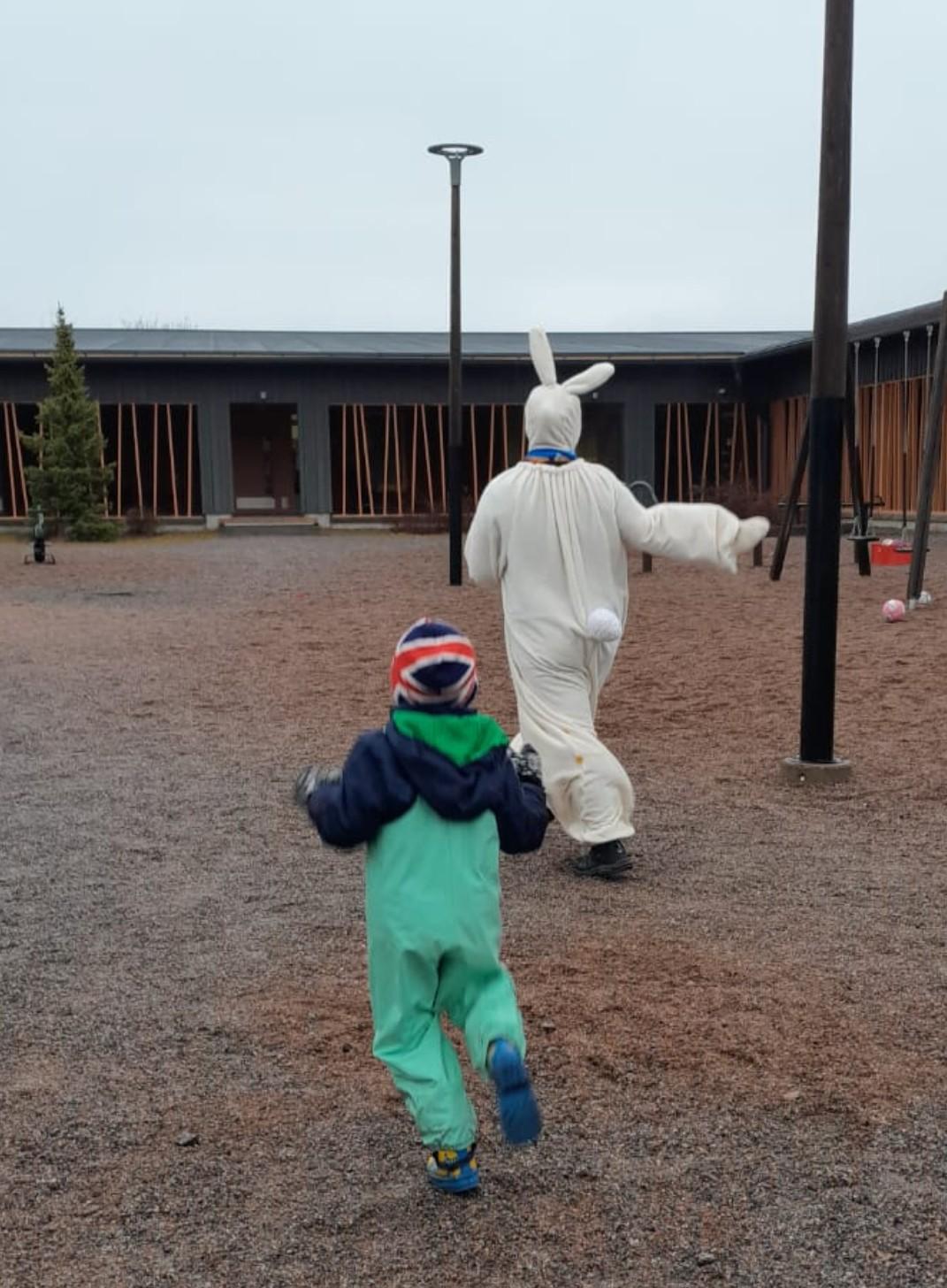 Jekku-jänö ja lapsi juoksevat Tainionkosken päiväkodin pihalla.