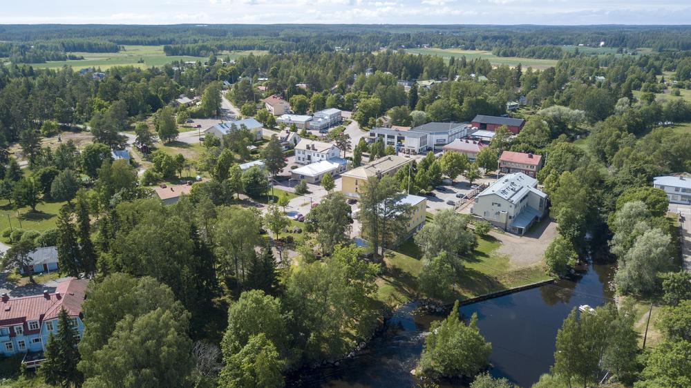 Ilmakuva vehreästä, kesäisestä Virojoesta, jossa useita erilaisia rakennuksia ja joki.