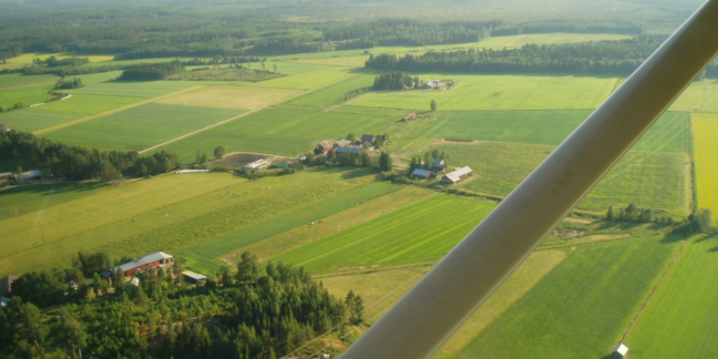 Ilmakuva, jossa vehreää peltomaisemaa.