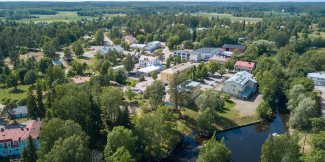 Ilmakuva vehreästä, kesäisestä Virojoesta, jossa useita erilaisia rakennuksia ja joki. 