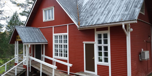 Punavalkoinen suuri hirsitalo.