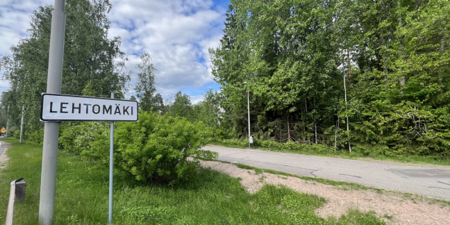 Vehreä lehtipuumaisema, jonka keskellä pyörä- ja kävelytie. Oikealla "Lehtomäki" -kyltti.