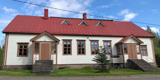 valkoinen puurakennus, jossa kaksi porstuaa, punainen katto ja ruskeat ikkunanpielet.