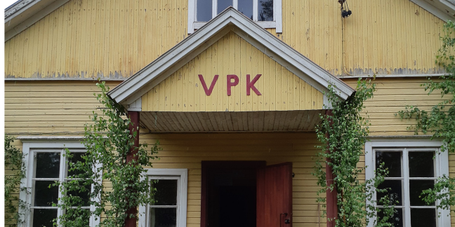 Keltainen puutalo, jonka edustalla kirjaimet "VPK".