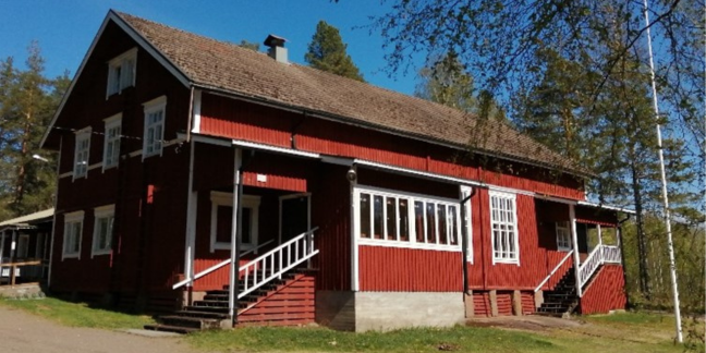 Punavalkoinen hirsitalo, jossa kaksi kuistia ja portaikkoa.