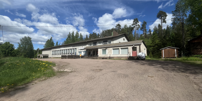 Suuri, vaalea kivirakennus kesäisessä maisemassa. 