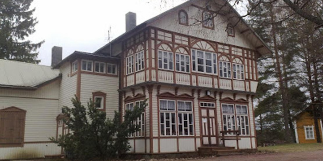 Puinen, vaalea, koristeellinen vanha talo. 