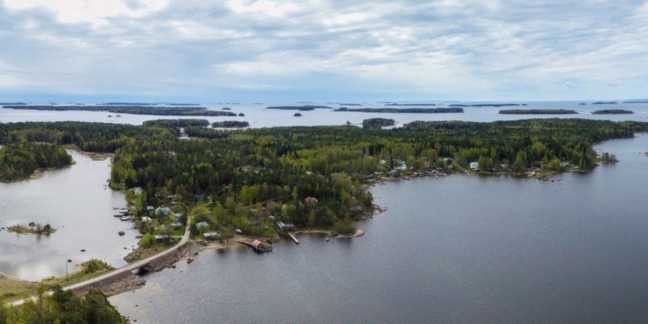 Ilmakuva saaresta, jossa paljon puita ja hieman taloja, meren ympäröimänä.
