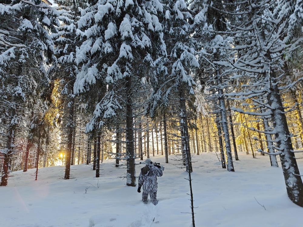 Mies kävelee lumisessa metsässä