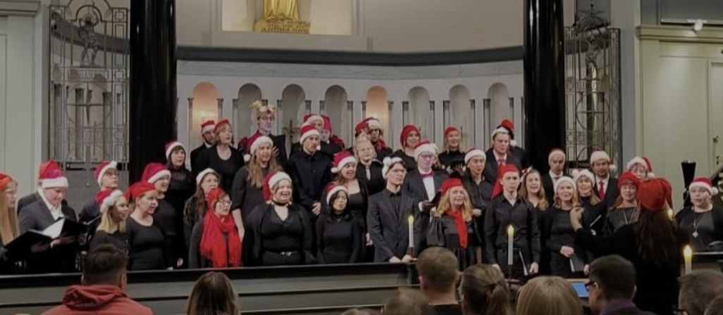 Kuoro esiintymässä joulukonsertissa tonttulakit päässä