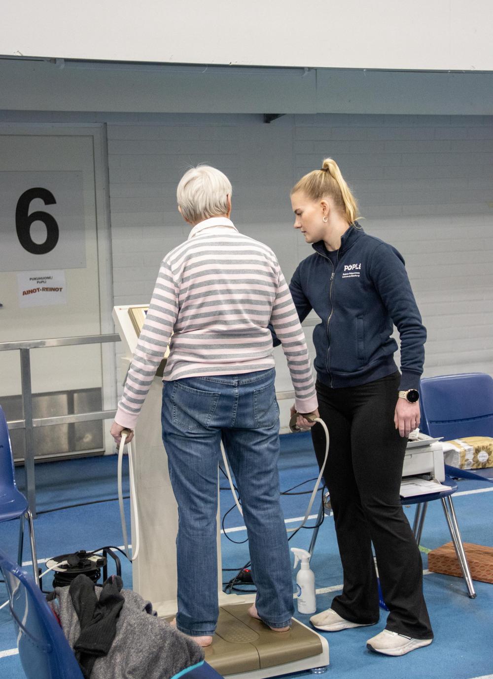Tapahtumahallissa henkilö ohjaa InBody-mittauksen tekemisessä.