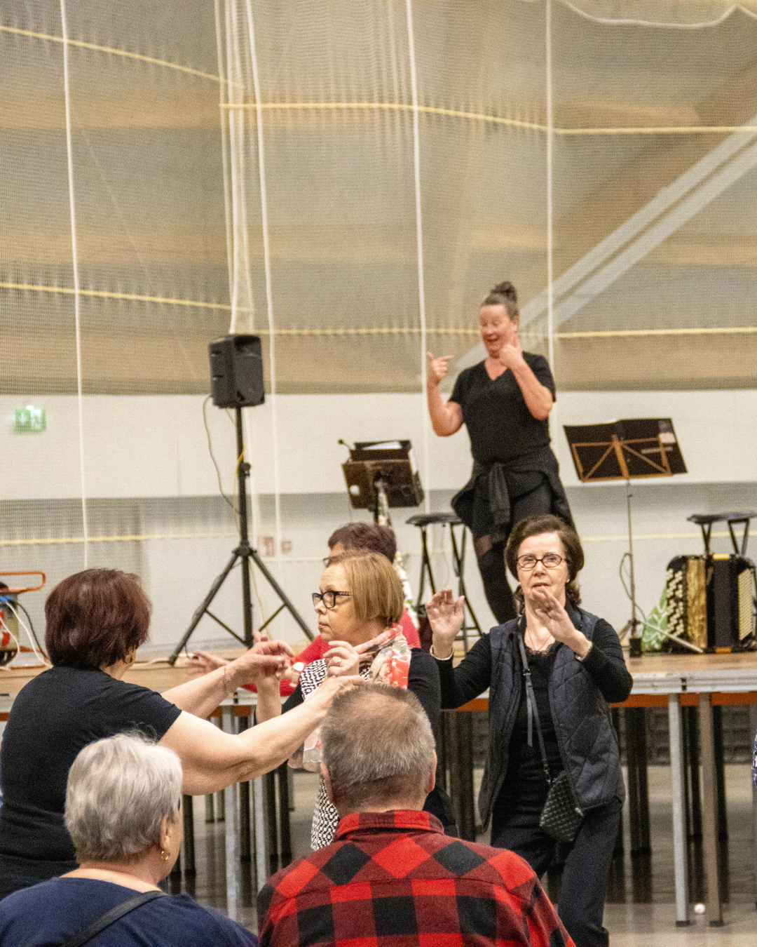 Ohjattu tanssihetki tapahtumahallissa, osallistujat liikkuvat ohjaajan johdolla.