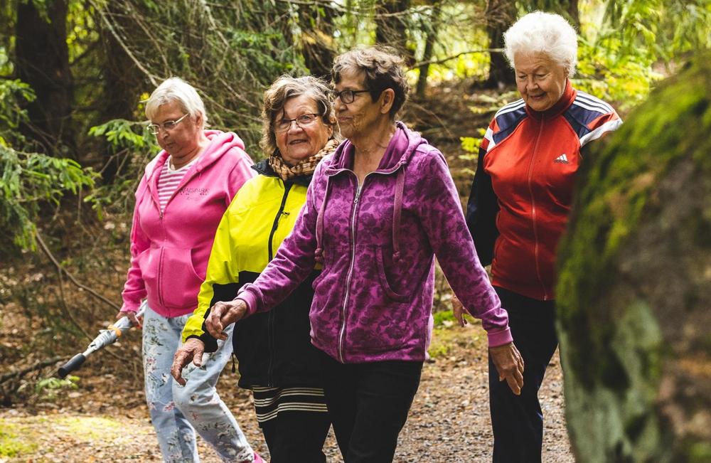 Seniori-ikäiset naiset kävelevät syksyisessä luonnossa liikuntavaatteissa. 