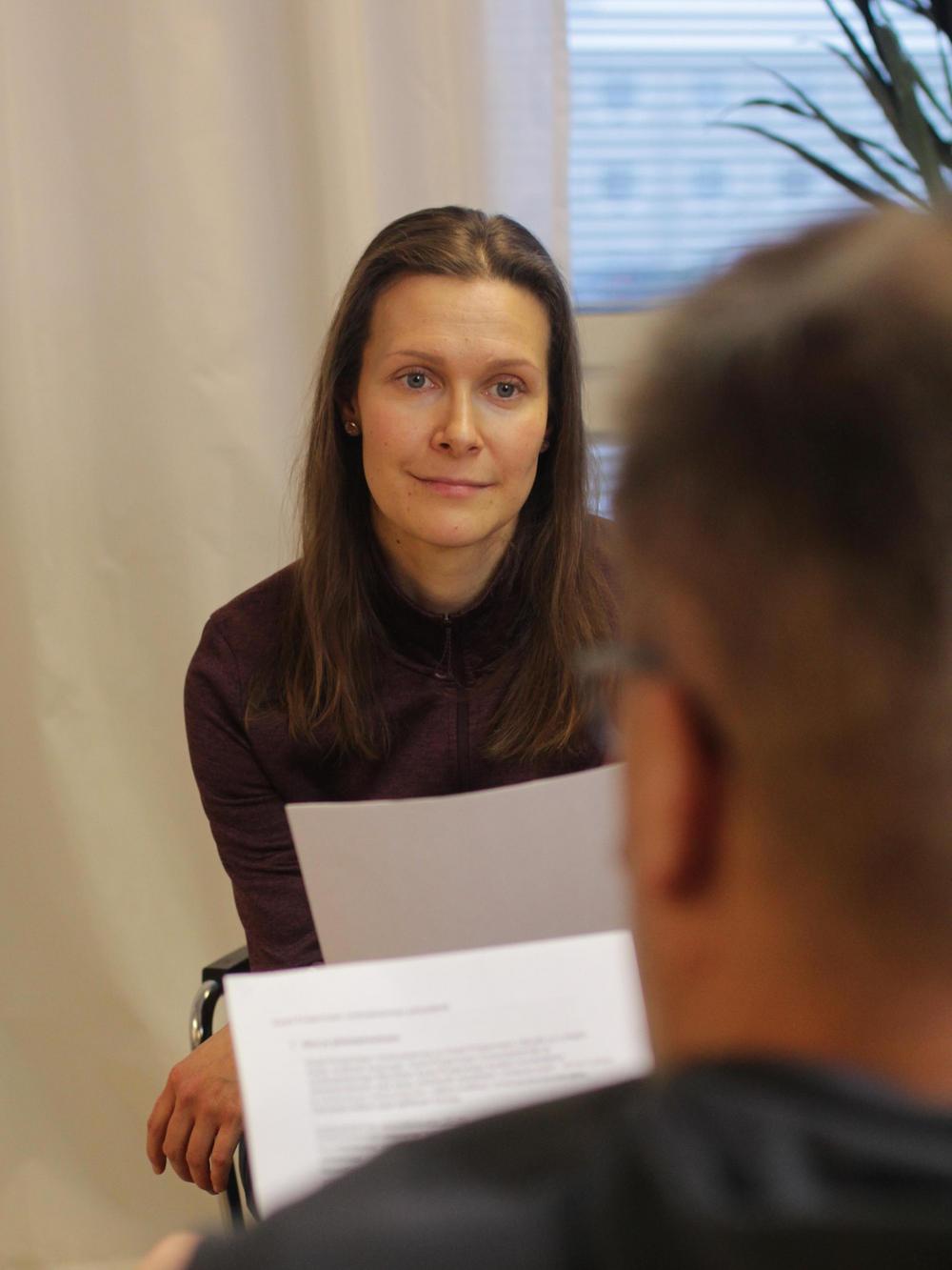Kaksi henkilöä istuu kasvokkain toisiinsa nähden sisätiloissa.