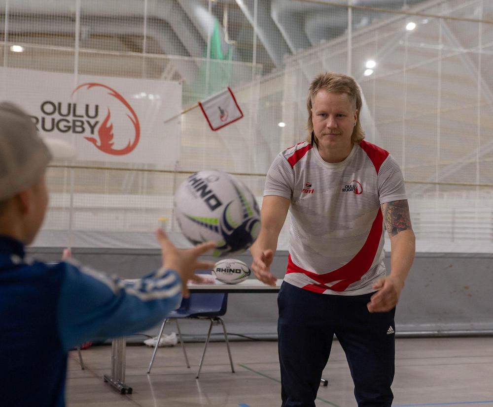 Tapio Ruha koppaa rugbypallon Ouluhallin yleisurheilupuolella.