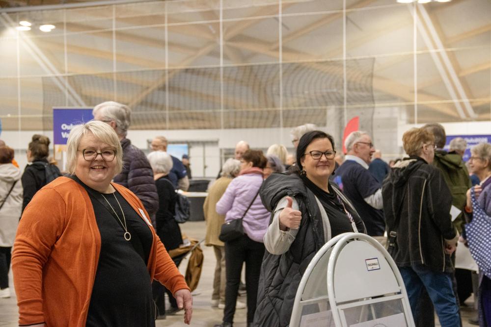 Iloisia henkilöitä kuvan etualalla tapahtumahallissa. Taustalla esittelypisteitä ja muuta yleisöä.