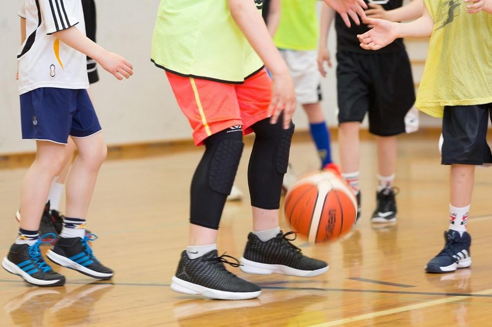 Nuoret pelaavat koripalloa liikuntasalissa.