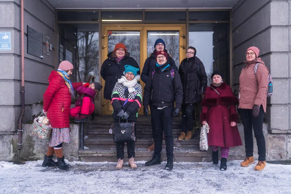 Ryhmä erilaisia ihmisiä, joiden kasvot näkyvät. Yhden ihmisen kasvot peittää kokonaan sateenkaarivärinen pipo.