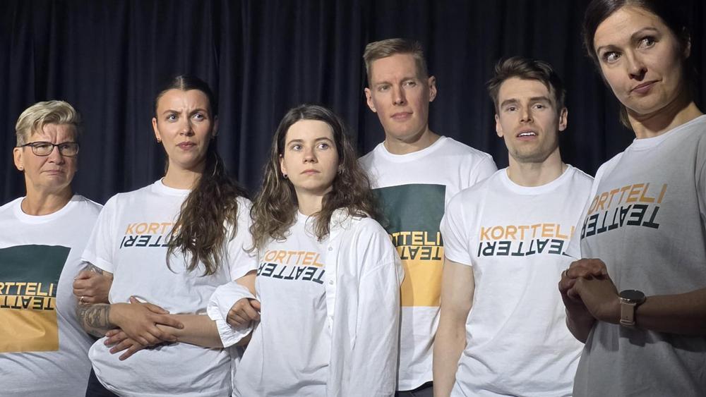 Kuusi Kortteliteatterin harrastajaa seisovat lavalla rivissä. Kaikilla on katseet oikealle, kuin siellä olisi jotain merkityksellistä katsottavaa. Näyttelijöiden katseet on vakavat ja dramaattiset, ikäänkuin he vaatisivat vastausta. 