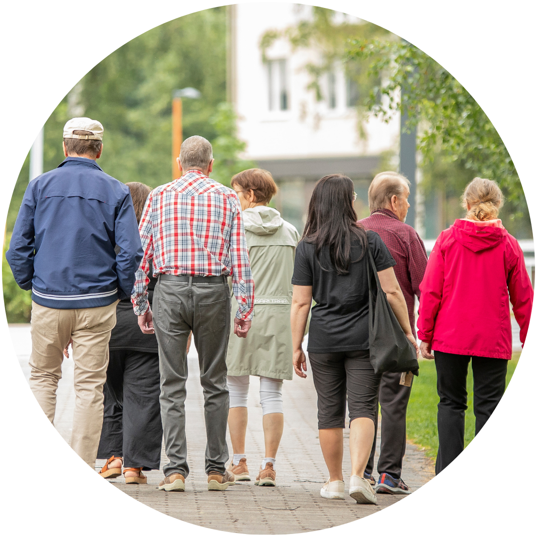 Joukko hymyileviä erin ikäisiä ihmisiä kävelee kaupungilla. Kaksi etummaista katsovat toisiaan silmiin hymyillen.