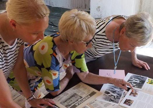 Kolme aikuista tutkivat lehtiä ja miettivät menisivätkö jooga-, pilates-, tanssi-, keramiikka-, akvarelli-, makramee vai kitaran kunnostamisen kurssille.