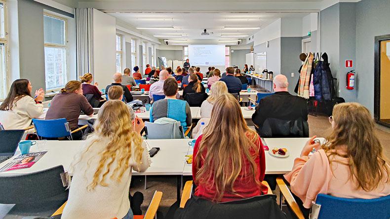 Uudelleenkäytön ammattilaisten seminaari Tampereella. Ihmisiä luentotilassa istumassa pöytien äärellä ja asiantuntia pitämässä luentoa taustalla.