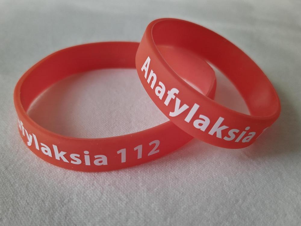 Kaksi punaista silikoniranneketta, joissa lukee Anafylaksia 112.