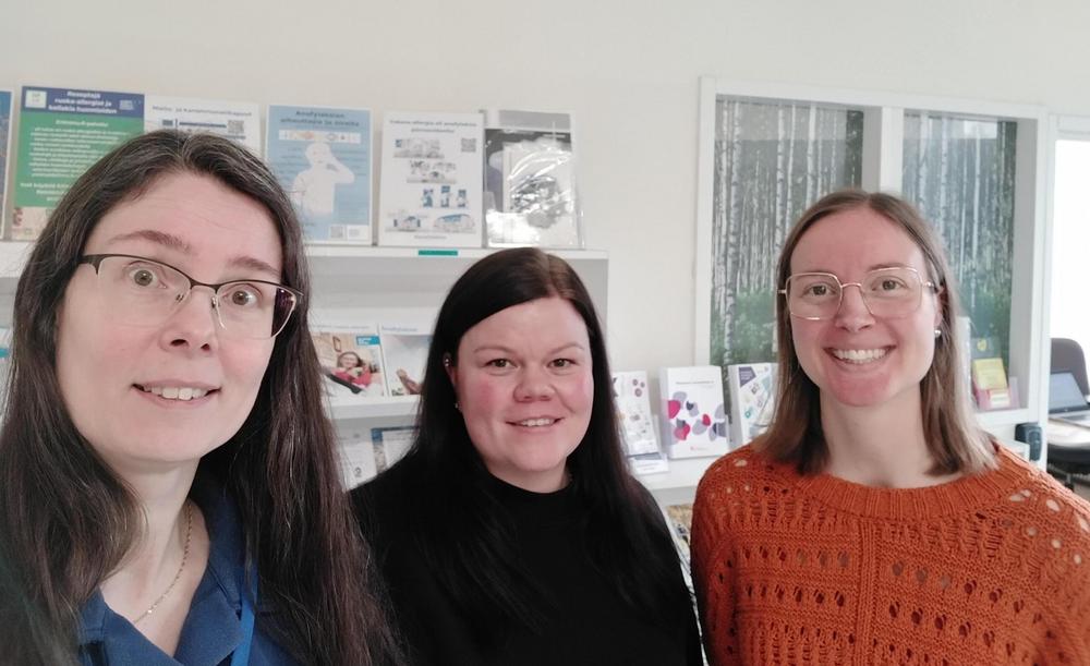 Kolme yhdistyksen työntekijää hymyilee.