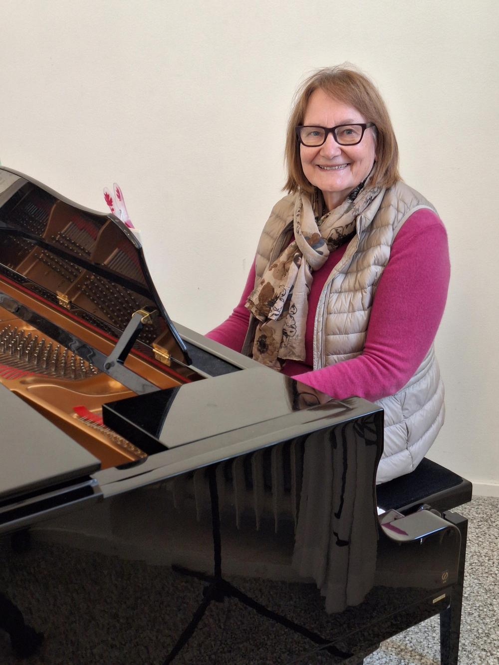 Vuokko Vänskä flyygelin äärellä säestää lauluja. 