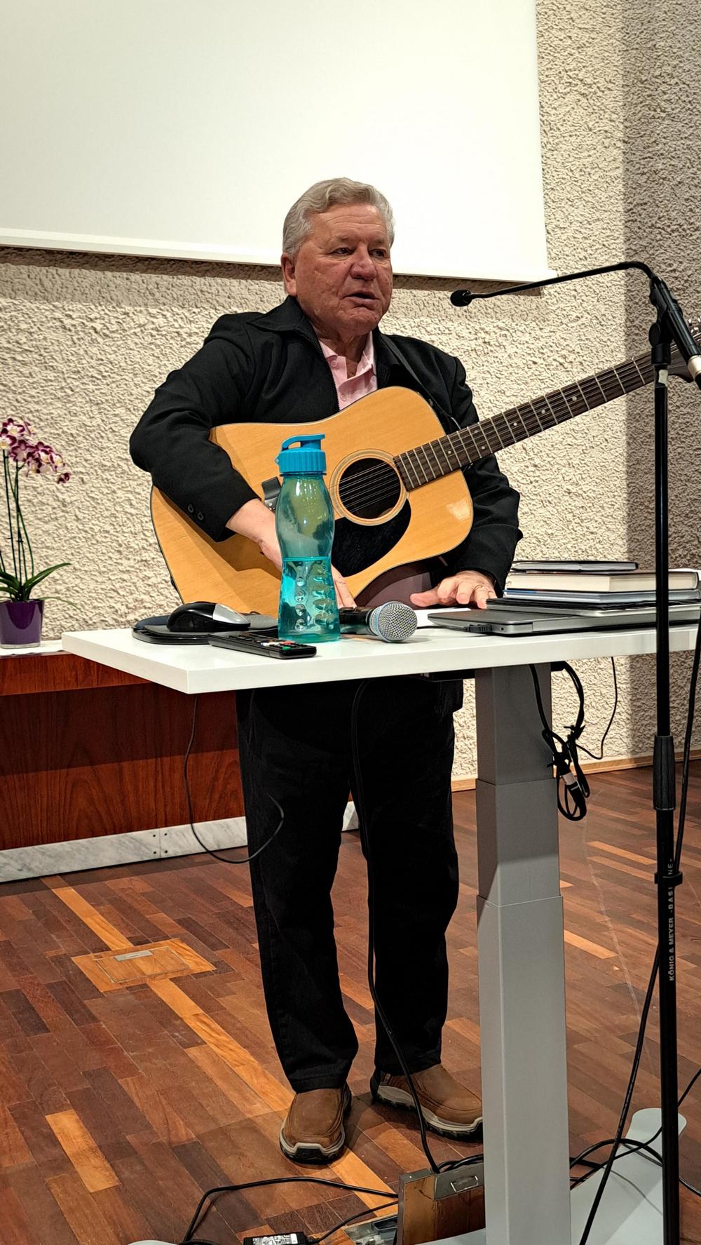 Hannu Mehtonen kitaran kanssa tummassa puvussa.