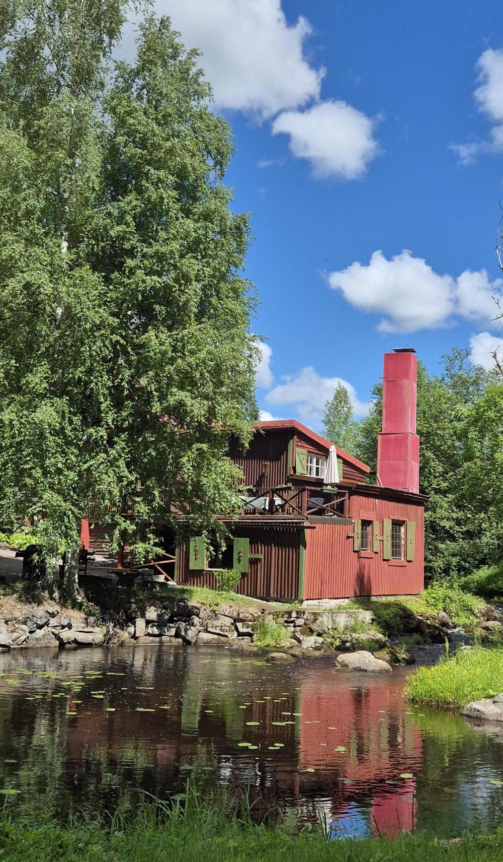 Kolme iloista ihmistä katselee kohti kameraa. Yhdellä heistä on paperi kädessään. He ovat sisätilassa.