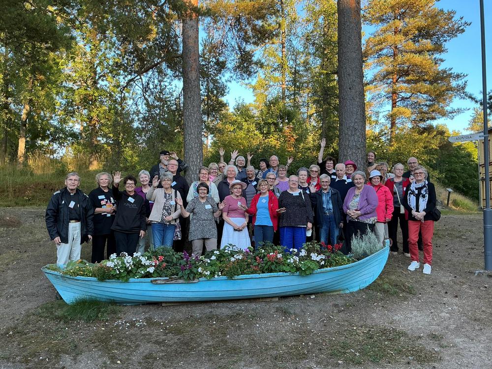 Iloisia ihmisiä ulkona. Osa vilkuttaa. n. 50 henkeä ryhmäkuvassa.