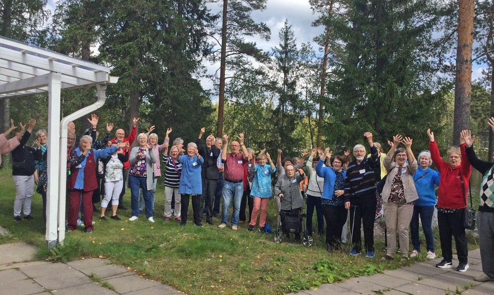 Noin neljäkymmentä eläkeläistä ulkona iloisina vilkuttamassa kuvaajalle