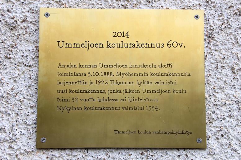 Kultainen muistolaatta, jossa lukee "2014, Ummeljoen koulurakennus 60v."