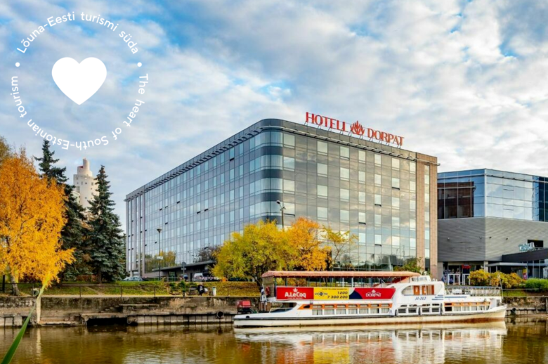 Hotellirakennus veden äärellä. Turistilaiva lipuu vedessä hotellin edessä.