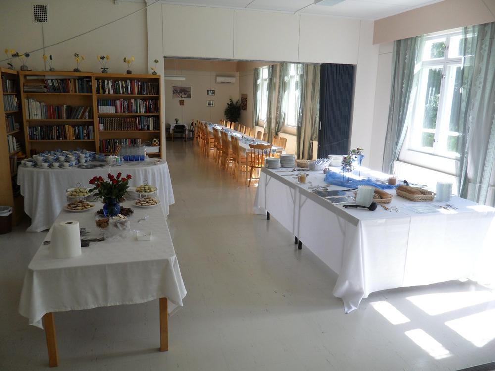 Avara sali, jossa useita pitkiä valkopöytäliinaisia pöytiä tuoleineen.