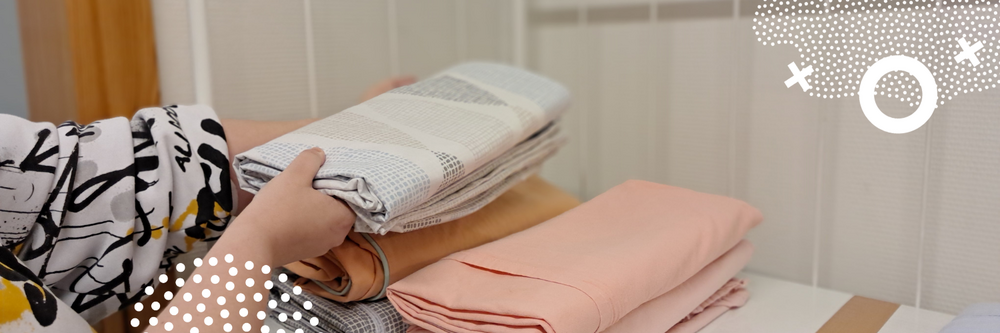 Kuvituskuva. Henkilö viikkaamassa pyykkiä siististi pinoihin.