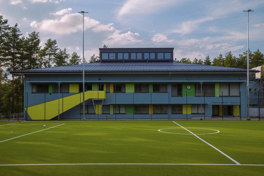 Moderni Kriivarin koulun rakennus ja sen edessä oleva vihreä tekonurmikenttä.