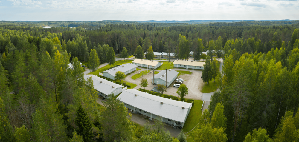 Ilmakuva rivitaloista runsaan puuston keskellä.